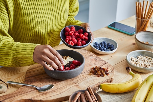 Close up of a person preparing a healthy bowl of oatmeal for breakfast with fruits and nuts
