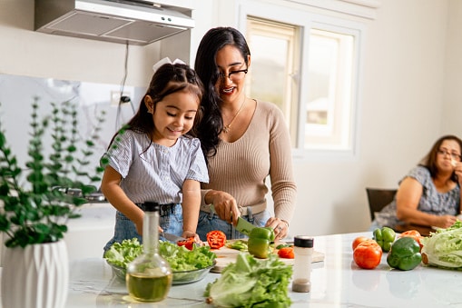 Happy mother and daughter preparing a healthy salad for lunch.